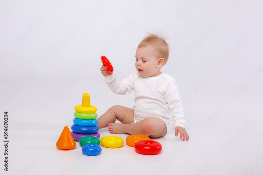 baby girl playing with colorful rainbow toy pyramid sitting on floor baby girl playing with colorful rainbow toy pyramid sitting on floor