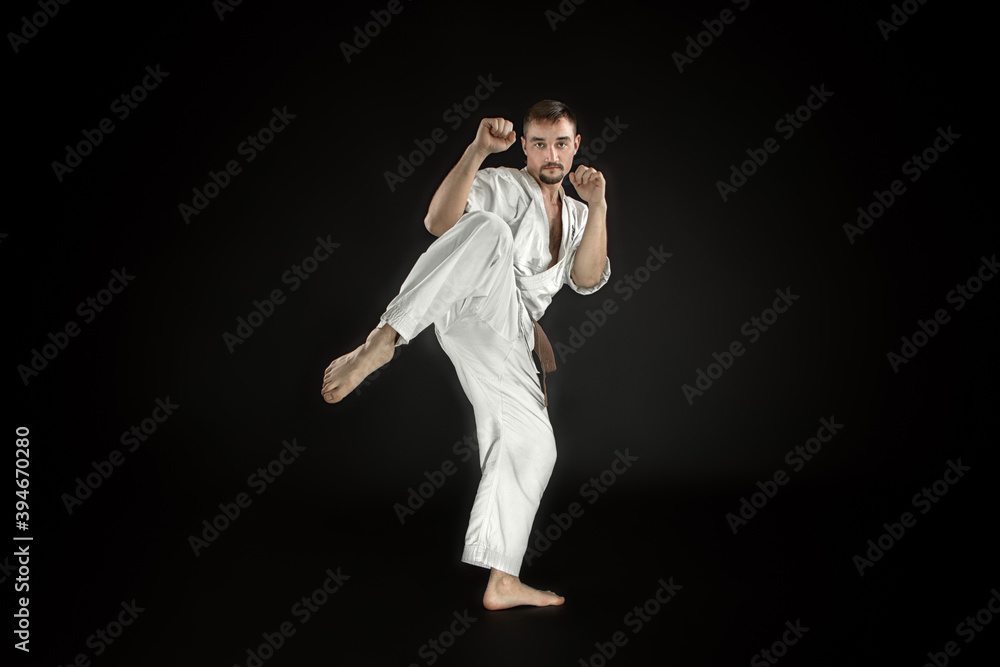 karate man training in-flight kick and posing on black background karate man training in-flight kick and posing on black background