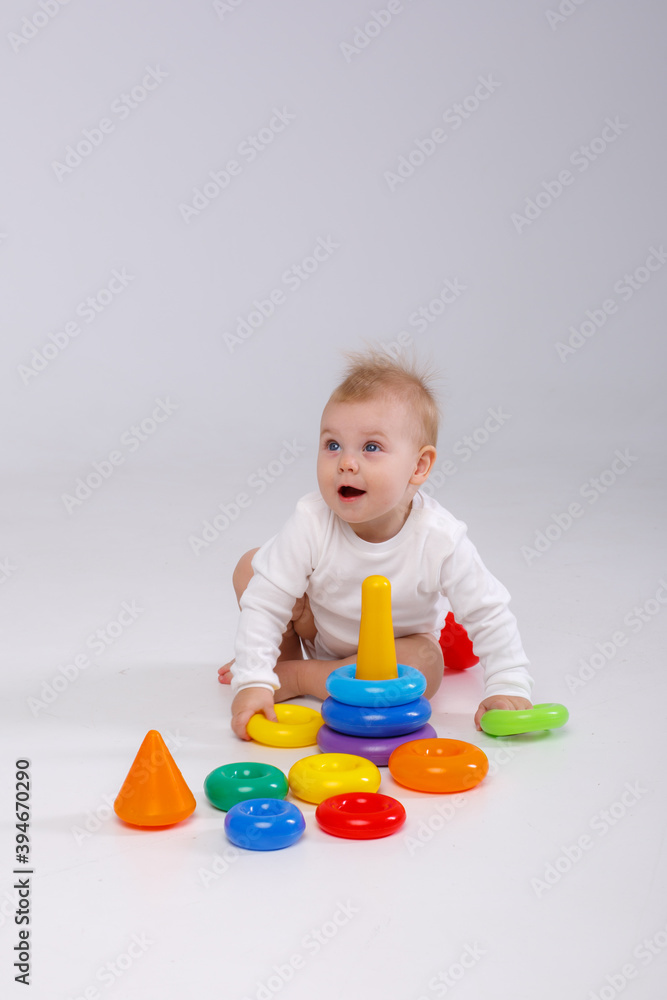 baby girl playing with colorful rainbow toy pyramid sitting on floor baby girl playing with colorful rainbow toy pyramid sitting on floor