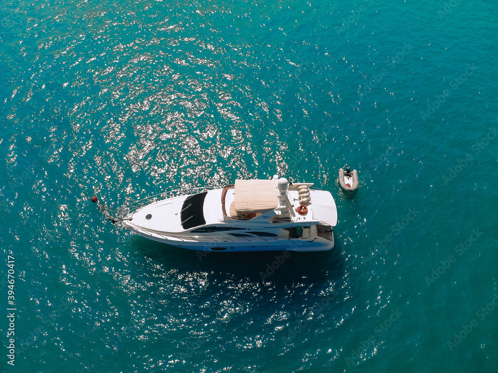 Adorable aerial top view photo of a laxury huge two-storey yach and a small boat next to it sailing across the deep blue sea Adorable aerial top view photo of a laxury huge two-storey yach and a small boat next to it sailing across the deep blue sea