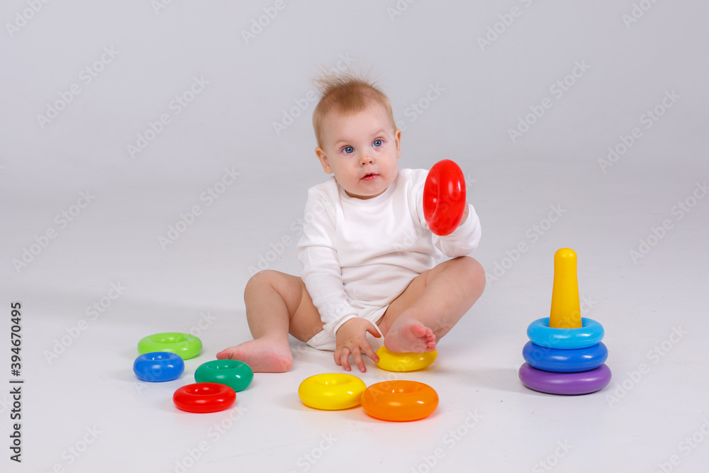 baby girl playing with colorful rainbow toy pyramid sitting on floor baby girl playing with colorful rainbow toy pyramid sitting on floor