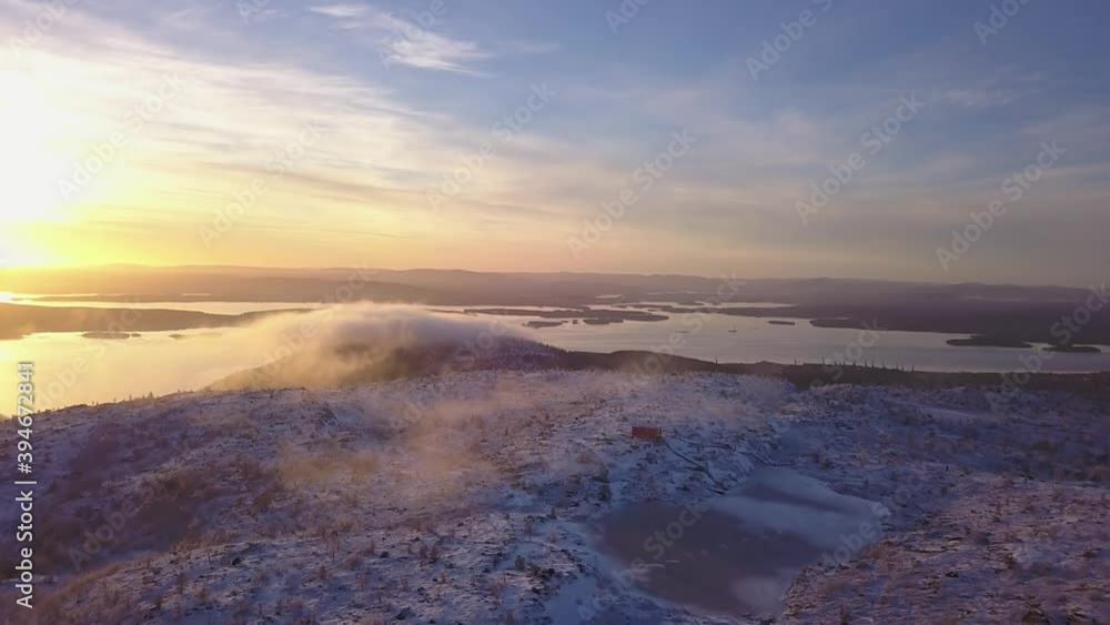 flying in a clear sky above low clouds over a snow-covered mountain illuminated by the rays of the sun flying in a clear sky above low clouds over a snow-covered mountain illuminated by the rays of the sun