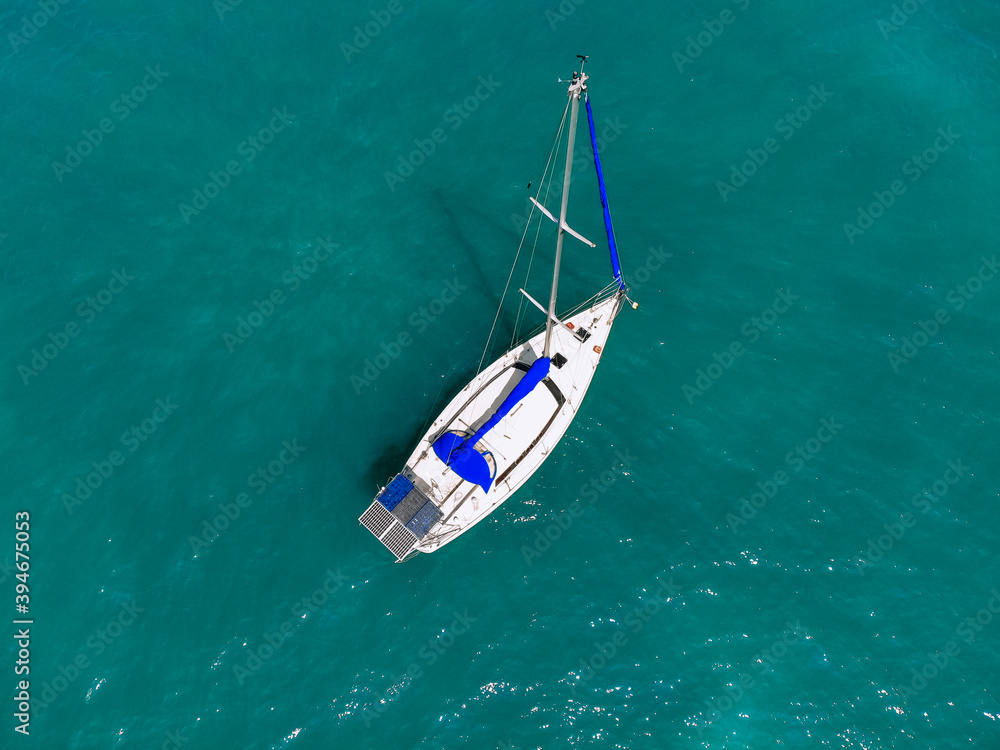 Aerial wonderful view of a enormous white and blue yacht sailing across the blue lagoona Aerial wonderful view of a enormous white and blue yacht sailing across the blue lagoona
