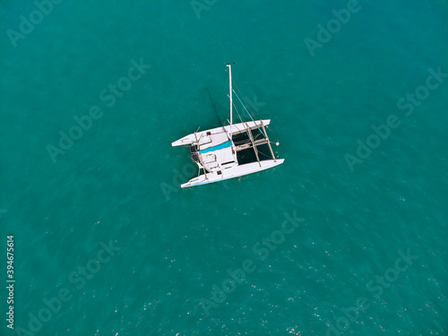 Bird's eyes view of the amazing white catamaran sailing across the blue lagoona. Top view.