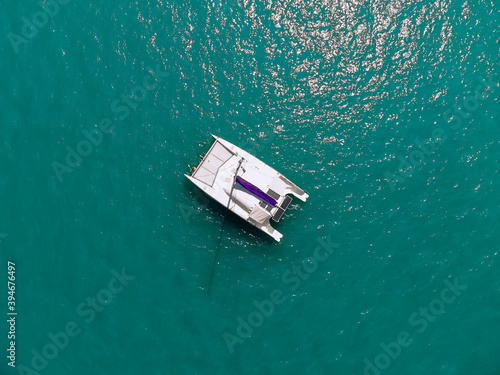 Picturesque top view of a huge white catamaran sailing across the deep sea. Aerial view.