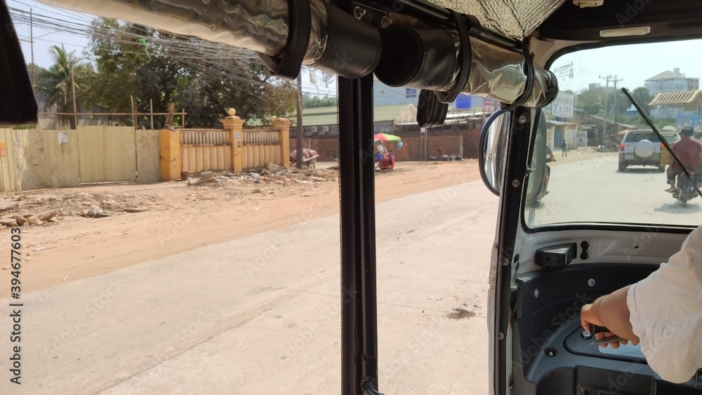 Riding a Tuk Tuk through the streets of Sihanoukville. Dirty street and traffic. Cambodia. South-East Asia