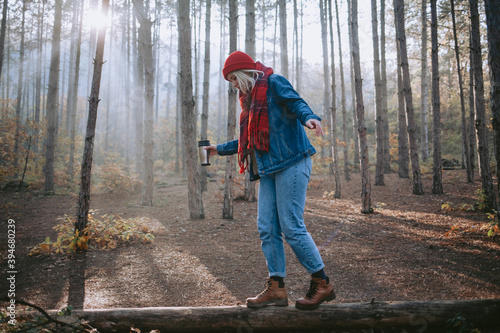 Woman walking on a fallen log in the forest