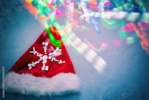 santa claus hat decorated with a snowflake of pills illuminated with colorful lights, blurred image