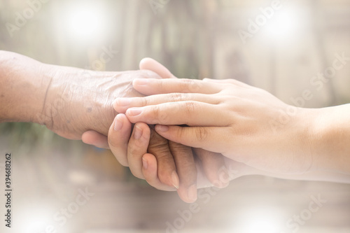 Caregiver, carer hand holding elder hand in hospice care. Philanthropy kindness to disabled concept.