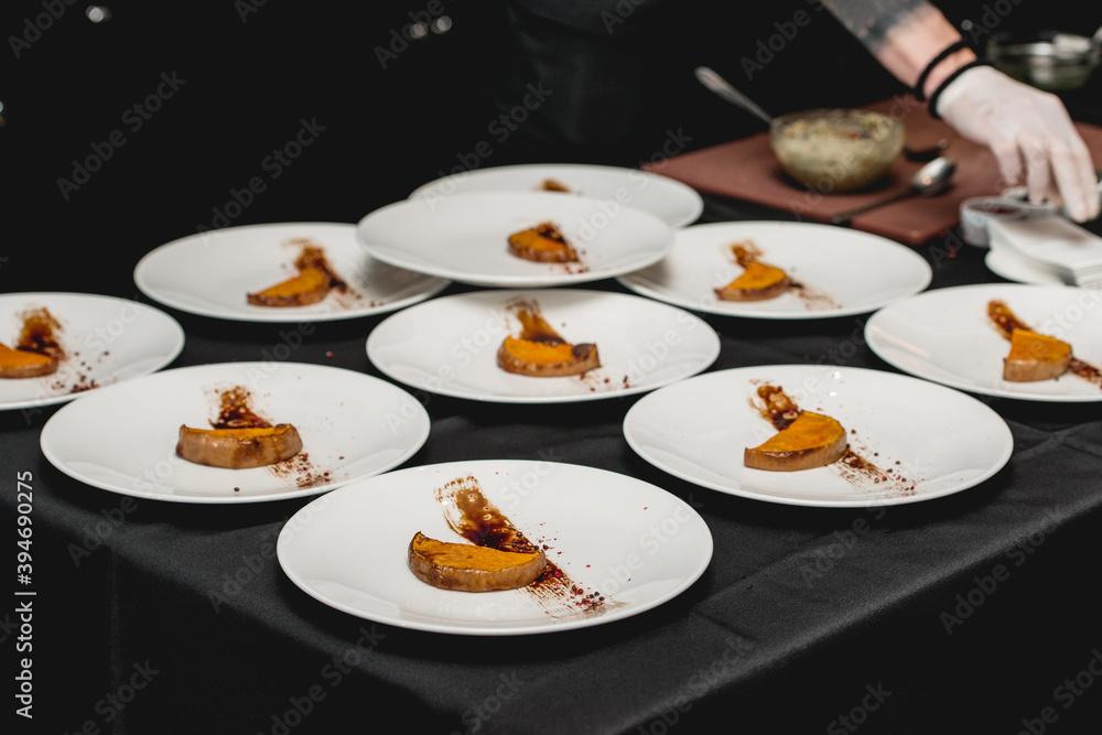 several white plates on a black table with baked sweet pumpkin and guacamole. Mexican cuisine at the restaurant several white plates on a black table with baked sweet pumpkin and guacamole. Mexican cuisine at the restaurant
