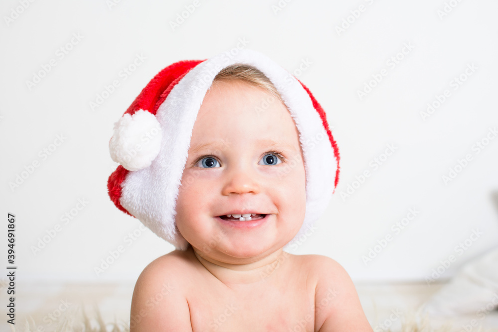 Portrait of a cute little baby smiling face with red Santa Claus hat isolated on white background. Christmas congratulations concept with copy space. Portrait of a cute little baby smiling face with red Santa Claus hat isolated on white background. Christmas congratulations concept with copy space.
