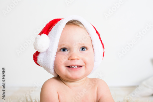 Portrait of a cute little baby smiling face with red Santa Claus hat isolated on white background. Christmas congratulations concept with copy space.