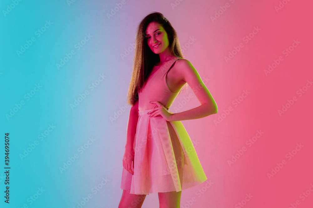 Confidence. Beautiful seductive girl in fashionable, romantic outfit on gradient pink-blue background in neon light. Half-length portrait. Copyspace for ad. Summer, fashion, beauty, emotions concept.