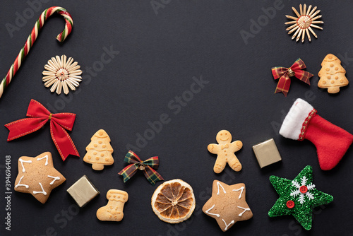 Christmas layout on a black background, New Year symbols: gingerbread cookies, bows, decorations for the New Year tree. mock up for design, place for text