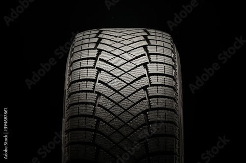 New friction winter tire on a black background, close-up front view