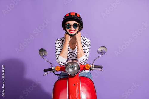 Portrait photo of happy female rider wearing helmet red lipstick sunglass sitting on motorbike smiling isolated on bright purple background