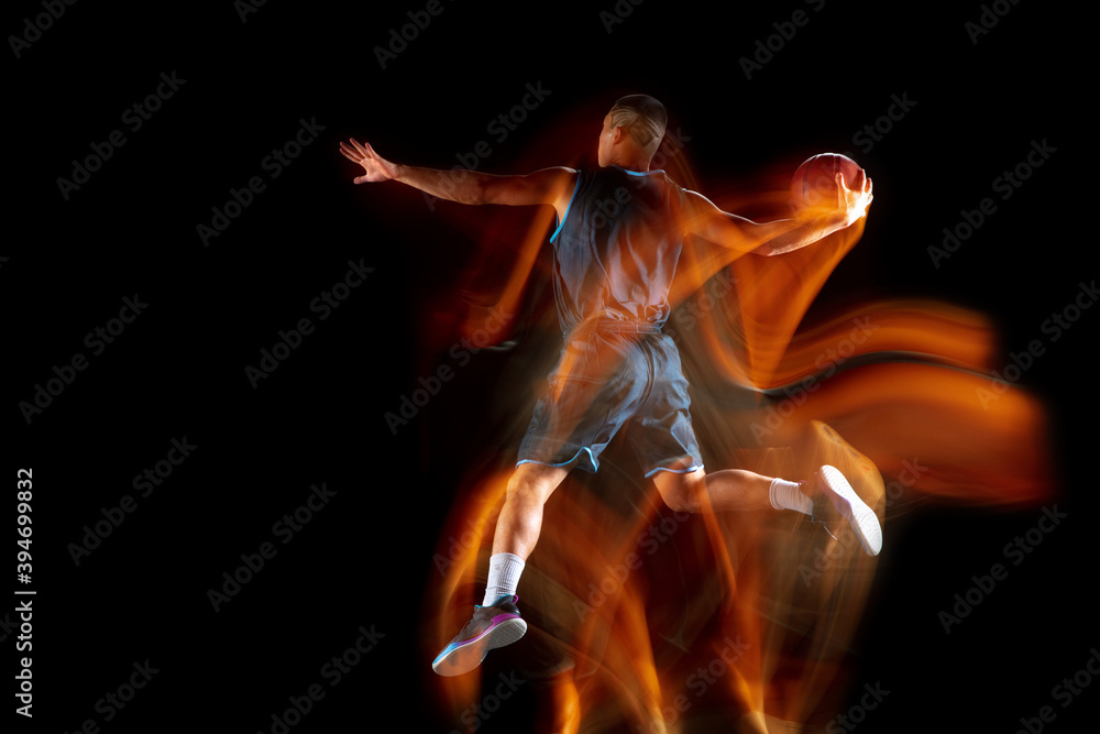 Obraz premium Mad playing Young east asian basketball player in action and motion jumping in mixed light over dark studio background. Concept of sport, movement, energy and dynamic, healthy lifestyle.