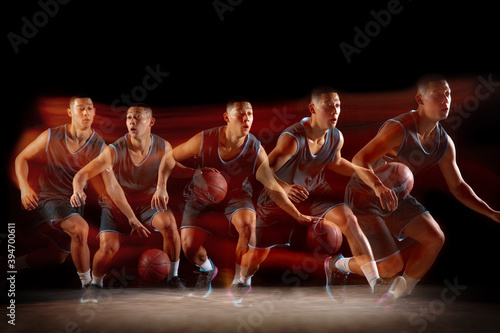Winner. Young east asian basketball player in action and motion jumping in mixed strobe light over dark studio background. Concept of sport, movement, energy and dynamic, healthy lifestyle.