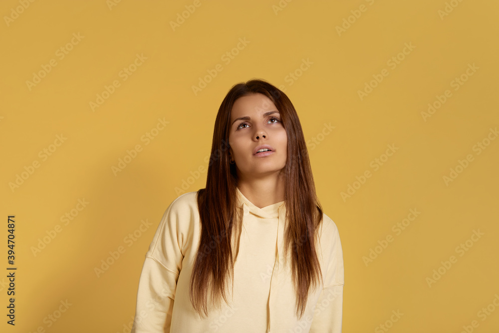 Displeased sleepy overworked caucasian woman in yellow hoodie looking up from weariness, feels fatigue after hard work. Isolated on a yellow background. Displeased sleepy overworked caucasian woman in yellow hoodie looking up from weariness, feels fatigue after hard work. Isolated on a yellow background.