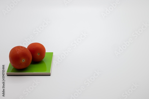 tomatoes on colored coasters and white background