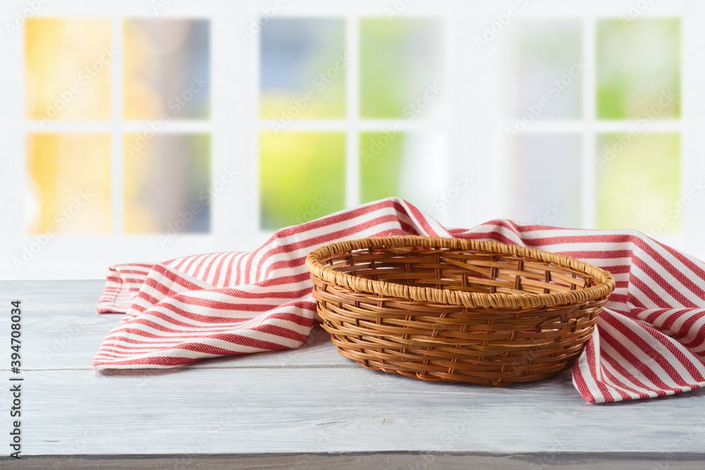 Obraz premium Empty basket with striped tablecloth over window background. Food or product display mock up for design.