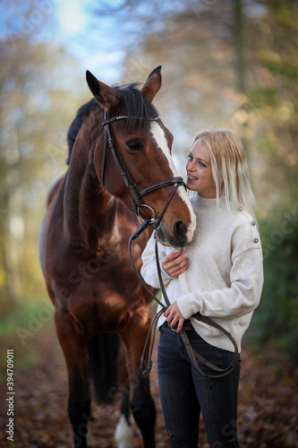 Young woman in close up with her horse on a forest path in autumn.. © RD-Fotografie