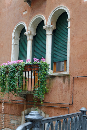 Venise, Italie, 27 février 2014 : Façade rouge, fênetres mauresques et un balcon avec plantes susspendues dans les ruelles de Venise photo