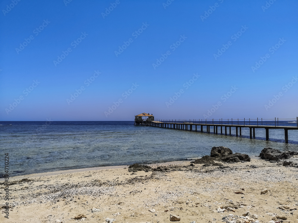 long jetty on sandy beach with blue sky at the sea