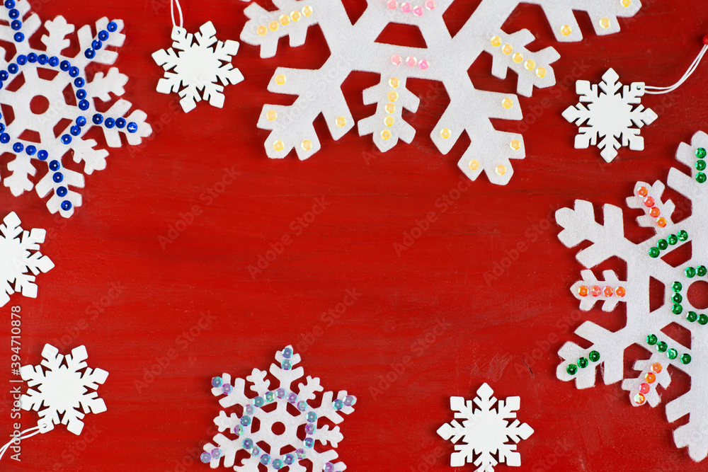 Decorative snowflakes and a spruce branch on a red wooden background.