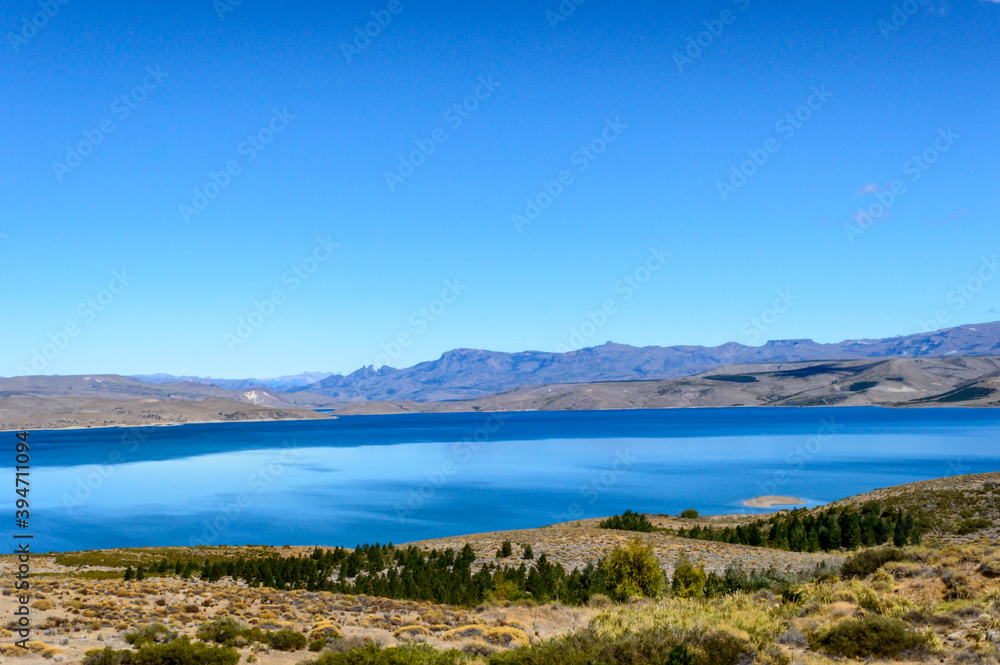 Landscape with wild flora and lake in the middle of mountains. Clear sky with some clouds. Sunny day and mountains-