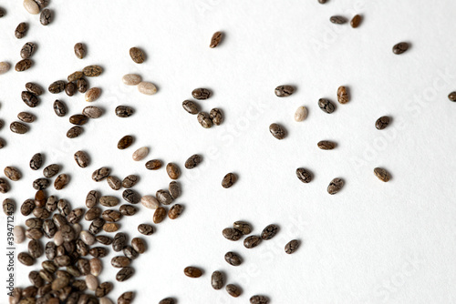 Macro photo of raw chia seeds randomly scattered on white background, copy space, superfood and diet concept