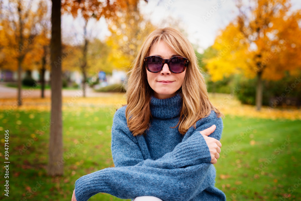 Portrait shot of confident mature woman wearing turtleneck sweater and sunglasses while standing in the park in autumn. Portrait shot of confident mature woman wearing turtleneck sweater and sunglasses while standing in the park in autumn.
