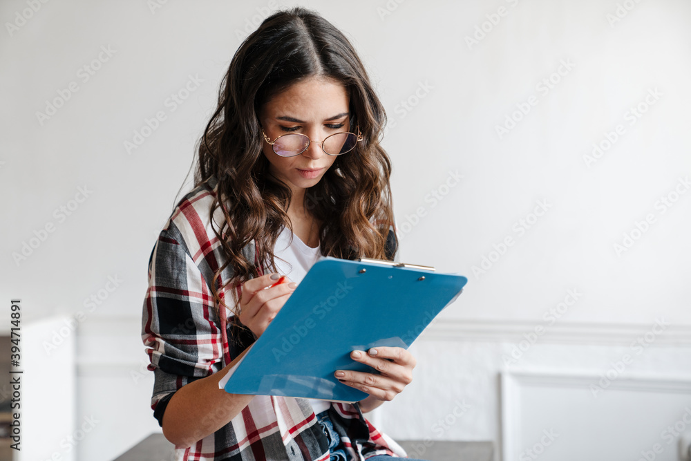 Serious nice woman thinking and writing down notes while sitting on table Serious nice woman thinking and writing down notes while sitting on table