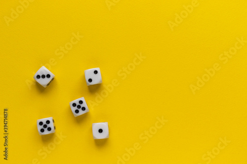 Five dice showing different sides on yellow background. Playing cube with numbers. Items for board games. Flat lay, top view with copy space.