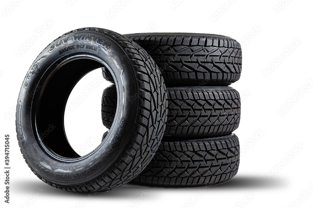 Stack of four new black tyres for winter car on white background
