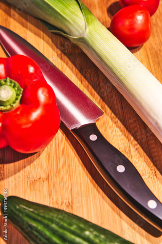 Vegetarian and vegan cooking with fresh vegetables. Leek, tomatoes, cucumber and paprika are freshly cut. Healthy and homemade cooking.