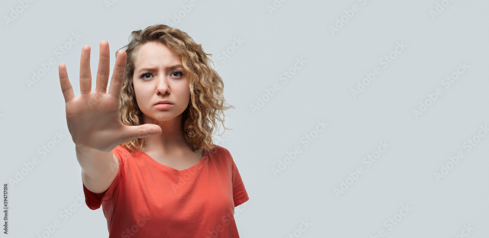 Image of serious blonde girl doing stop sign with palm of the hand. Studio shot white background. Copy space Image of serious blonde girl doing stop sign with palm of the hand. Studio shot white background. Copy space