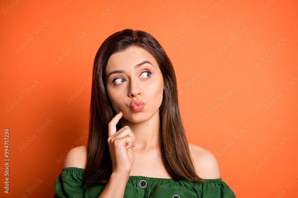 Photo portrait of cunning girl pouted lips looking empty space isolated on vivid orange color background Photo portrait of cunning girl pouted lips looking empty space isolated on vivid orange color background