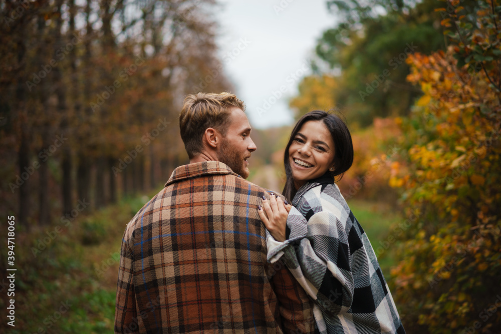Beautiful happy couple smiling and hugging while strolling in forest Beautiful happy couple smiling and hugging while strolling in forest