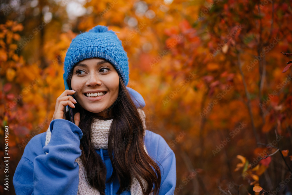 Happy woman talking on cellphone while strolling in autumn forest Happy woman talking on cellphone while strolling in autumn forest