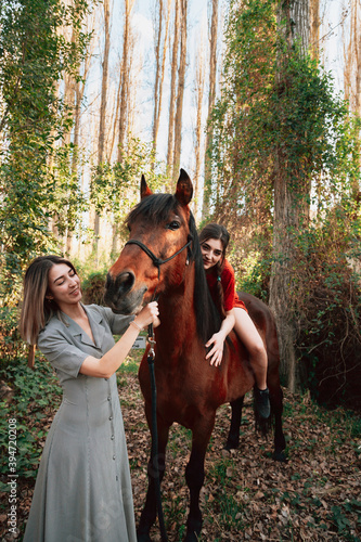 Two women friends chatting and taking a ride with their horse through the countryside © Manu Reyes