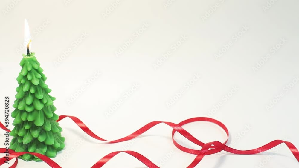Fast panning from left to right of burning candle in shape of fir tree with red ribbon Fast panning from left to right of burning candle in shape of fir tree with red ribbon