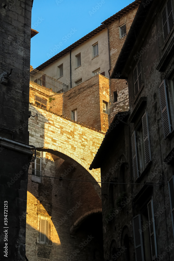 Stone arch on top of medieval building, illuminated by orange sunset light, city of Perugia, Umbria region, Italy