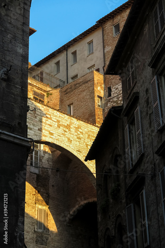 Stone arch on top of medieval building  illuminated by orange sunset light  city of Perugia  Umbria region  Italy