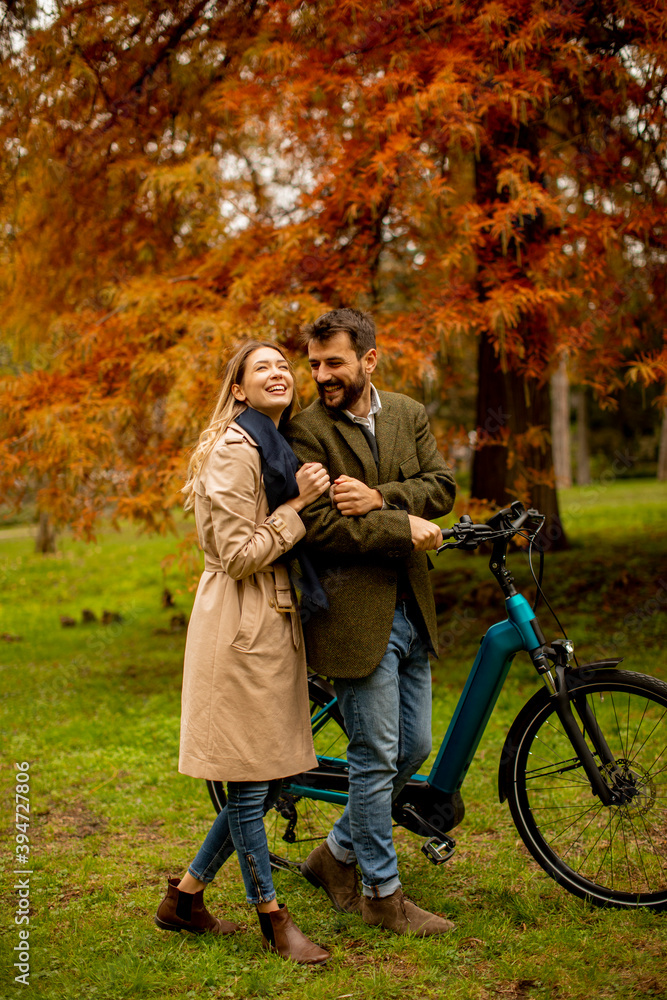 Young couple in the autumn park with electrical bicycle