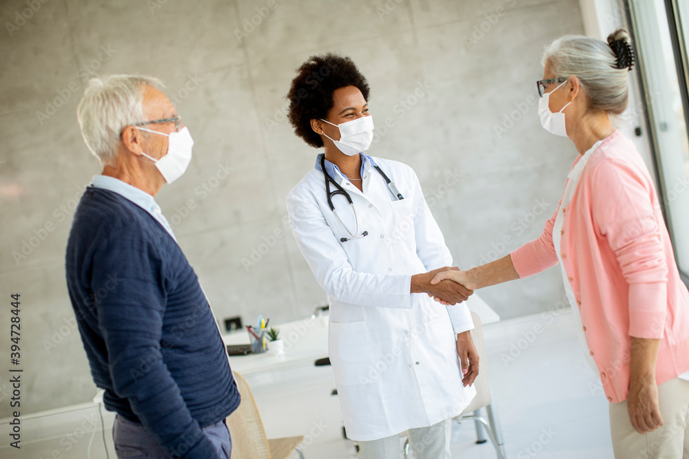Senior coule with protective facial masks receive news from black female doctor Senior coule with protective facial masks receive news from black female doctor