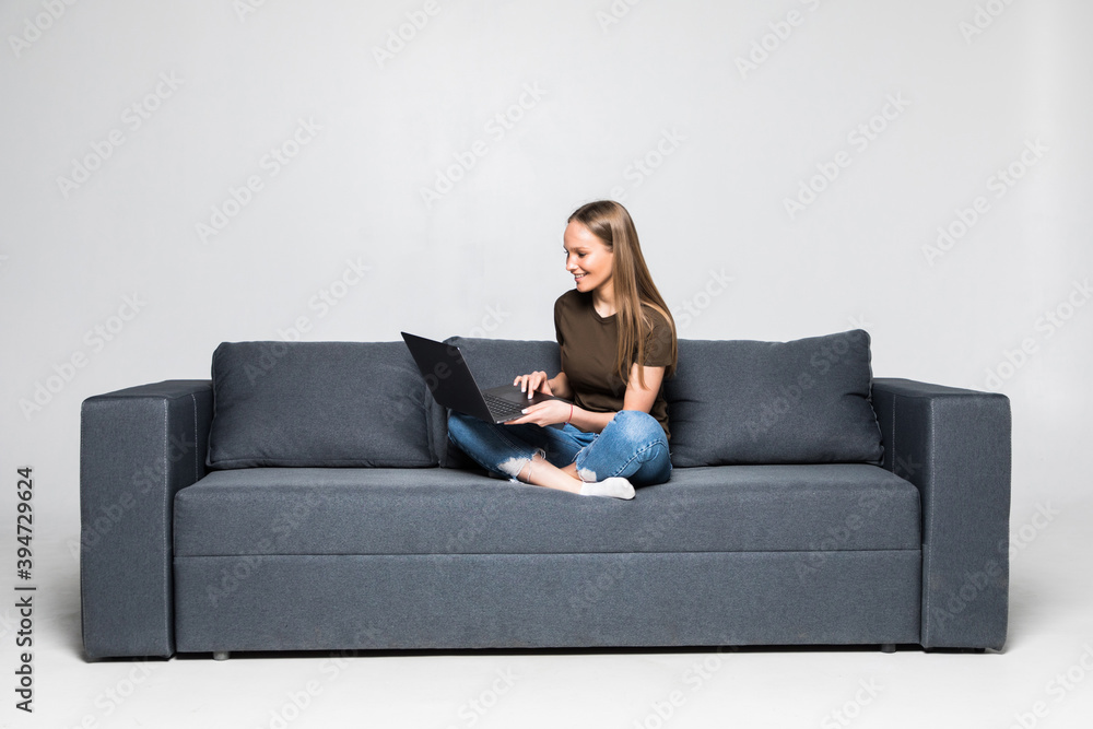 Woman lying on sofa at home working on laptop computer. Isolated on white background. Woman lying on sofa at home working on laptop computer. Isolated on white background.