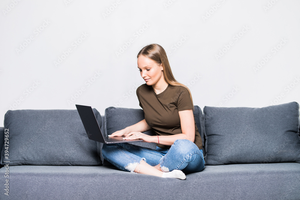 A pretty woman wearing casual clothes with laptop sit on sofa isolated on white background A pretty woman wearing casual clothes with laptop sit on sofa isolated on white background
