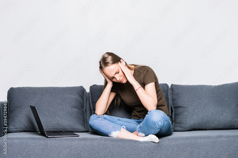 Sad young woman sitting on a modern sofa on white background Sad young woman sitting on a modern sofa on white background