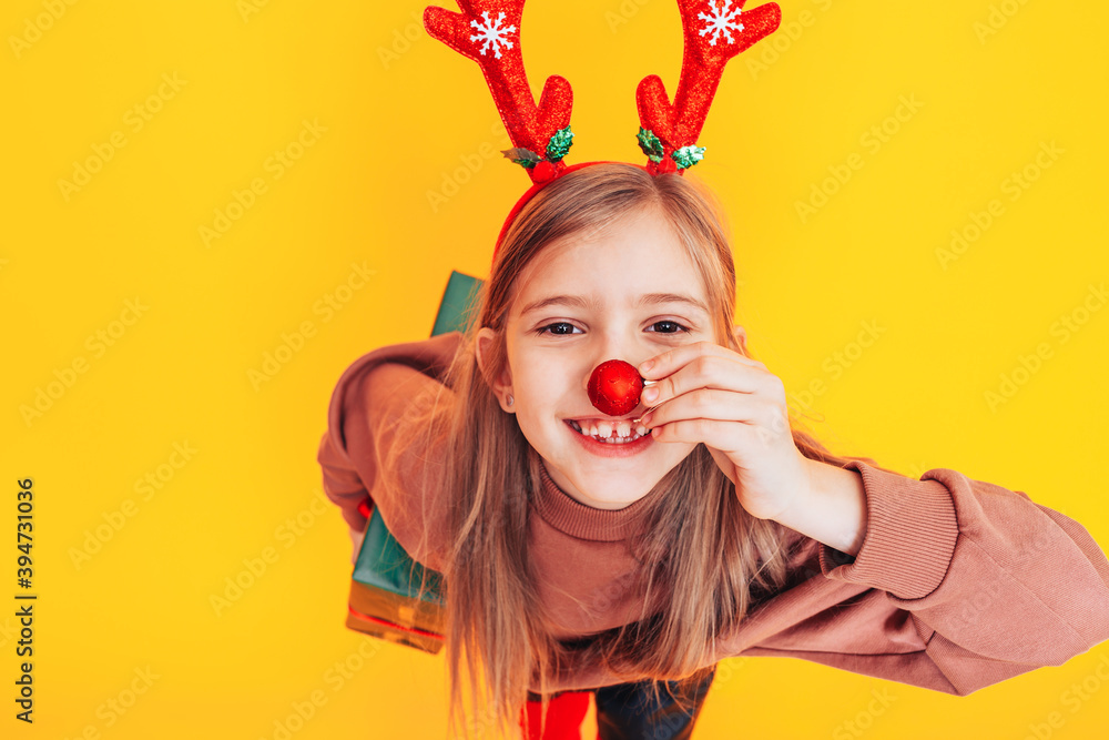 Surprised child holding a large box with a gift. There are Christmas antlers on the head. Christmas mood